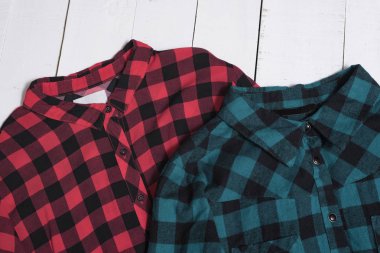 Fashion clothes. Collars of a red and green checkered shirt on white wooden floor planks clipart