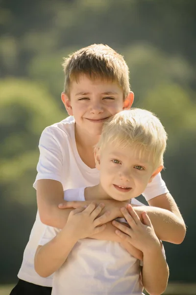 Два маленьких хлопчика обіймаються на відкритому повітрі. Концепція дружби та братерства — стокове фото