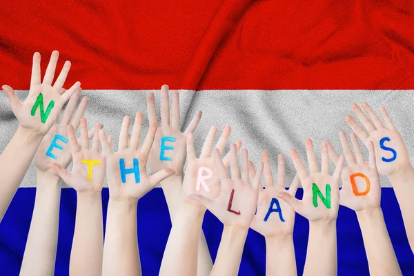 Prasasti Belanda di tangan anak-anak terhadap latar belakang bendera melambaikan Belanda — Stok Foto