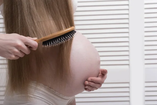 Mulher grávida penteando seu cabelo comprido. Close-up. Conceito de saúde — Fotografia de Stock