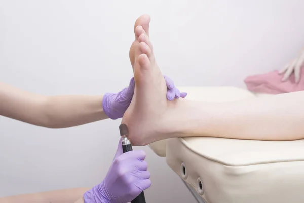 足の皮膚の治療プロセス。ペディキュア マシンで手袋をはめた手。クローズ アップ — ストック写真