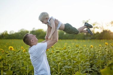 Mutlu baba bir yeşil alan ayçiçeği küçük gülen oğlu yukarı atma. Yakın çekim