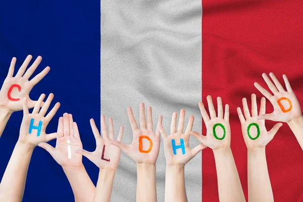Επιγραφή παιδική ηλικία στα χέρια των παιδιών στο πλαίσιο του μια κυματίζει σημαία της Γαλλίας — Φωτογραφία Αρχείου