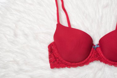 Dantel beyaz kürk üzerinde kırmızı bir sutyen parçası. Düz yatıyordu. Moda iç çamaşırı kavramı.
