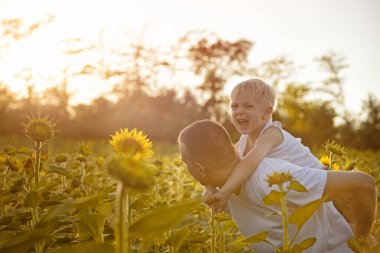 Günbatımında çiçek açan ayçiçeği yeşil bir alanda yürüyüş arka oğluyla mutlu baba
