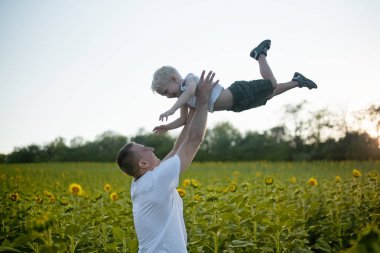 Mutlu baba bir yeşil alan ayçiçeği küçük gülen oğlu yukarı atma