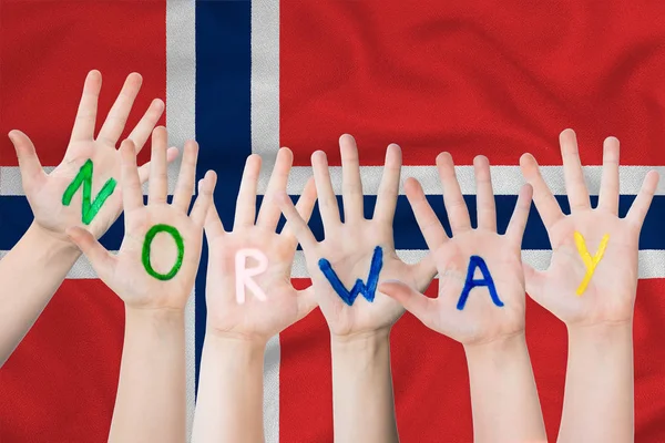 Noruega inscripción en las manos de los niños sobre el fondo de una bandera ondeante de Noruega —  Fotos de Stock
