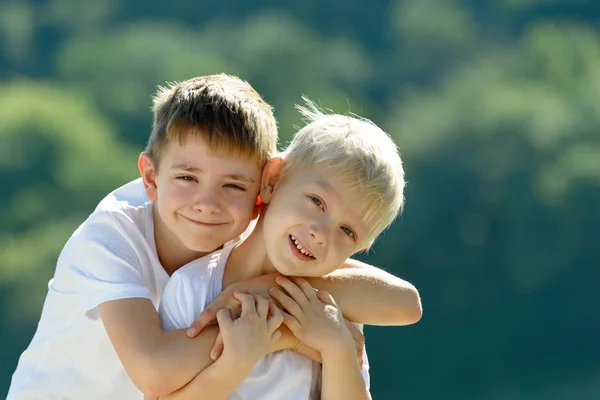 Dwóch małych chłopców są przytulanie na zewnątrz. Pojęcie przyjaźni i braterstwa — Zdjęcie stockowe