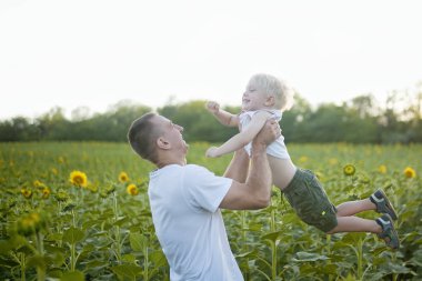 Mutlu baba oğlunun ayçiçekleri alanı üzerinde yukarı atar