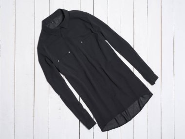 Beyaz ahşap arka planda siyah bluz. Moda konsepti.