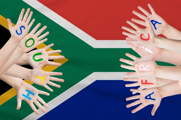 Inscripción de Sudáfrica en las manos de los niños sobre el fondo de una bandera ondeante de Sudáfrica — Foto de Stock