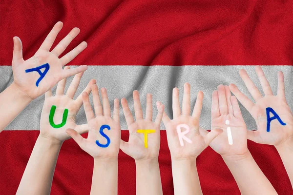 Austria inscripción en las manos de los niños sobre el fondo de una bandera ondeante de la Austria — Foto de Stock