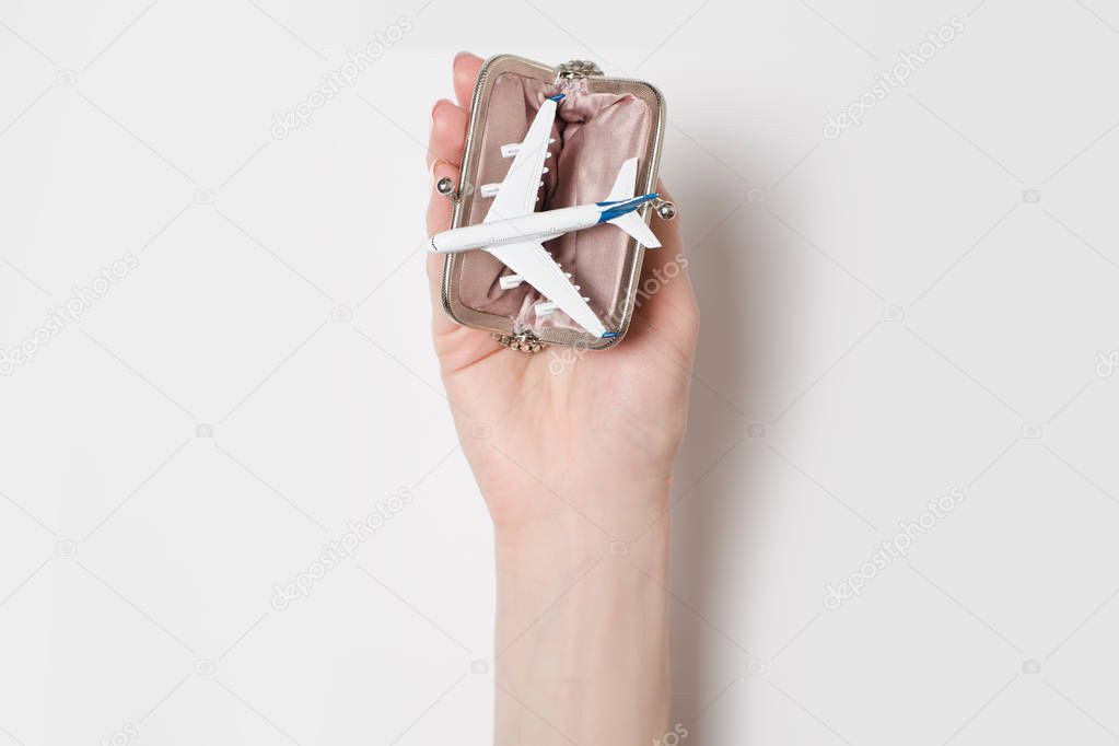 Passenger plane in the wallet on the female palm on a light background. Cheap flights
