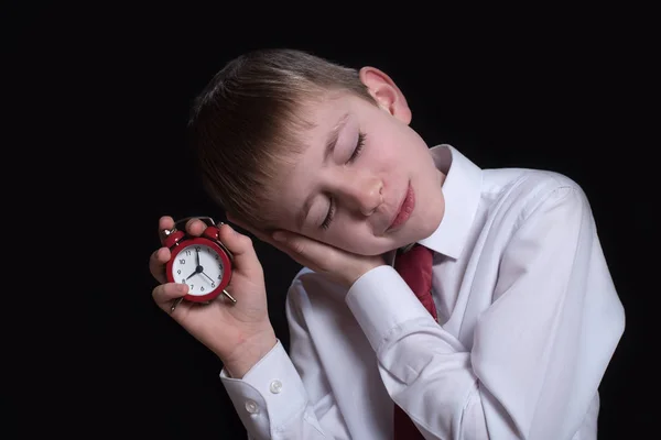Сплячий школяр з червоним будильником в руках. Ранкова концепція. Чорний фон. ізольовані — стокове фото