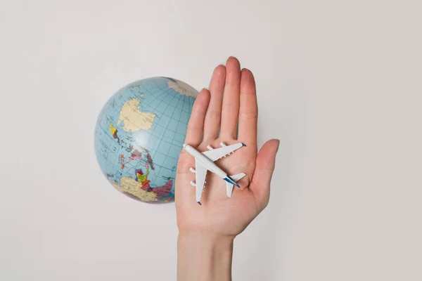 Aviones de pasajeros en la palma femenina en el fondo del globo. Concepto de viaje aéreo sobre un fondo claro — Foto de Stock