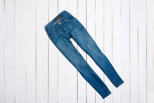 Blue jeans on white wooden background. Fashion concept.