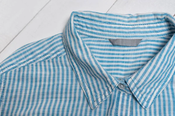 Метка на голубой полосатой хлопковой рубашке. Концепция моды. Закрыть — стоковое фото