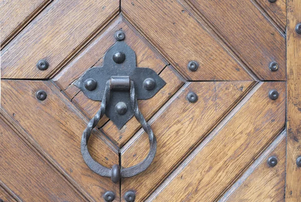 Σφυρήλατο μεταλλικό χερούλι πόρτας με ένα δαχτυλίδι σε μια ξύλινη πόρτα — Φωτογραφία Αρχείου
