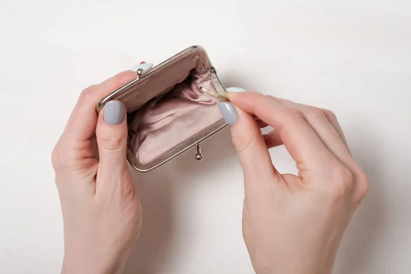 Рука кладе монету в порожній відкритий металевий гаманець на світлому фоні — стокове фото