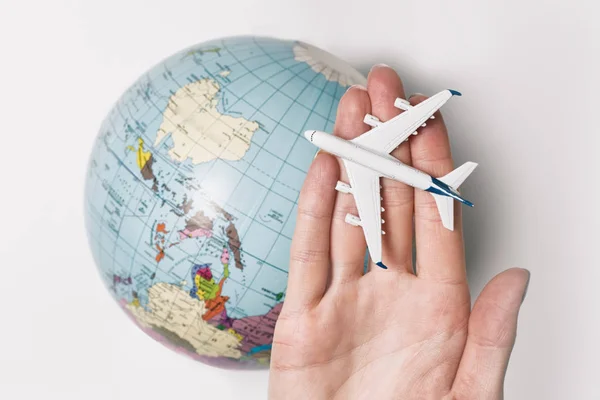 Passenger aircraft on the female palm on the background of the globe. Concept of air travel on a light background — Stock Photo, Image