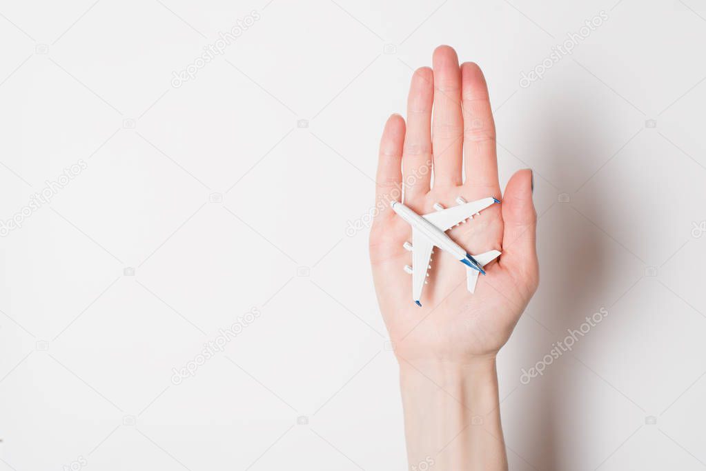 Airliner on the female palm on a light background. Concept of safe flights