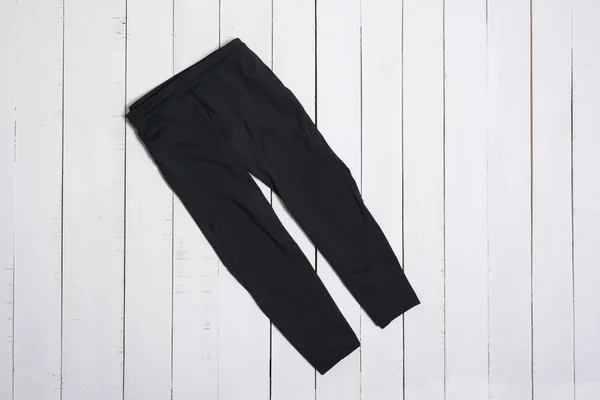 Czarne legginsy do siłowni na białym tle drewnianym. Koncepcja odzieży mody. — Zdjęcie stockowe