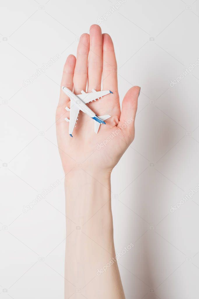 Airliner on the female palm on a light background. Concept of safe flights
