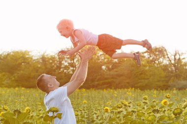 Mutlu baba bir yeşil alan ayçiçeği küçük gülen oğlu yukarı atma. Yakın çekim