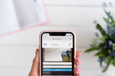 Kharkiv, Ukrayna - 10 Nisan 2019: Kadın ekranda legacy.com site ile Apple iphone X tutar.