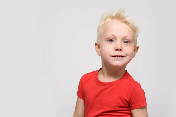 Um rapaz loiro sorridente de t-shirt vermelha. Retrato. Espaço para SMS. Fundo branco — Fotografia de Stock