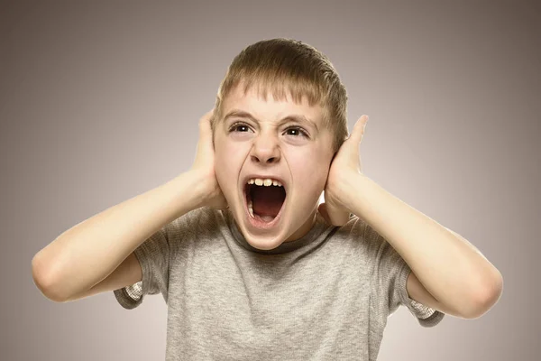 Ragazzo chiuso le orecchie con le mani e grida furiosamente. Scolaretto cattivo. Paura — Foto Stock