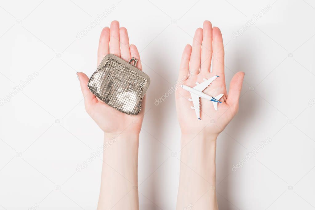 Passenger plane and wallet on female palms on a light background. Cheap flights