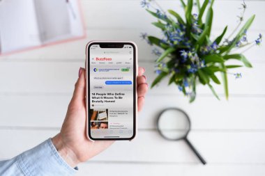Kharkiv, Ukrayna - 10 Nisan 2019: Kadın ekranda Buzzfeed.com site ile Apple iphone X tutar. Arama sayfası