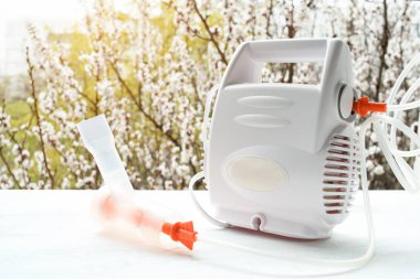 Çiçek açan bir ağacın arka planında maskeli nebülizör. Bahar alevlenme