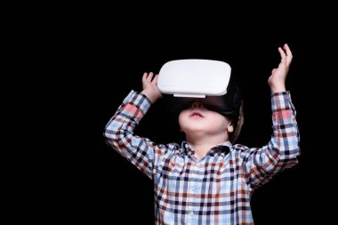 Sanal gerçeklik gözlüğü ile küçük sarışın çocuk bakar. Ekose gömlek. Siyah arka plan