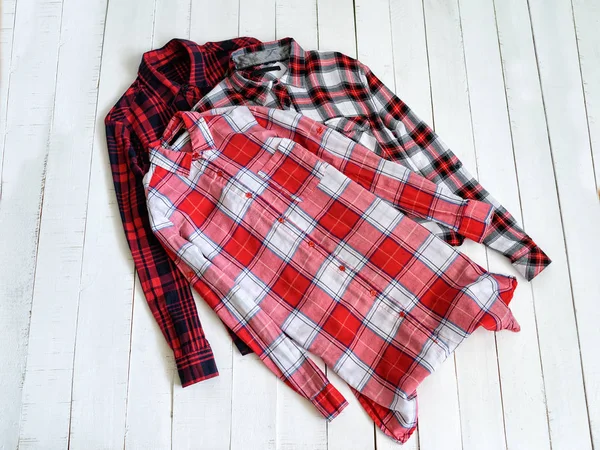 Clothes concept. Three checkered shirts on a wooden background. Top view