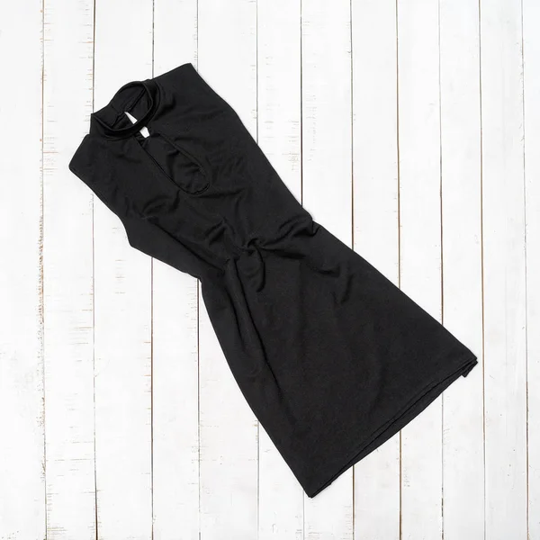 Kleines schwarzes Kleid auf weißem Holzgrund. Kleidungskonzept — Stockfoto