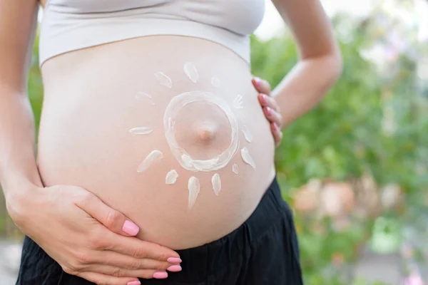 Crema solar pintada sobre una barriga femenina embarazada. Concepto de embarazada. Primer plano —  Fotos de Stock