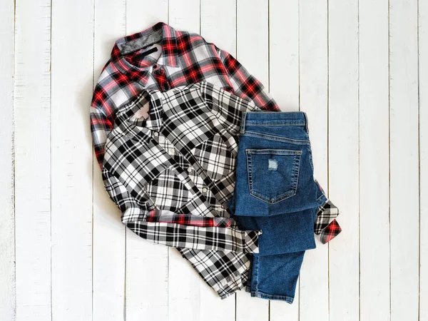 服のコンセプト。木製の背景に2枚のチェッカーシャツとジーンズ。トップビュー — ストック写真