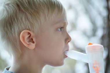 Çiçekli ağaçların arka planda maske inhaler nefes sarışın çocuk. Evde tedavi. Önleme. Yakın çekim