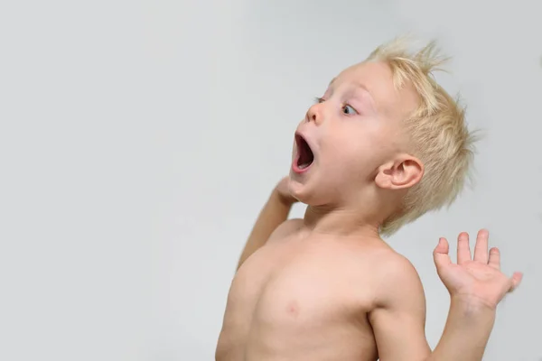 Verrast kleine blonde jongen met open mond en naakte rompstaat in de buurt van een ventilator. Zomer concept — Stockfoto