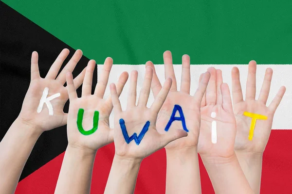 Inschrift Kuwait auf den Händen der Kinder vor dem Hintergrund einer schwenkenden Fahne des Kuwait — Stockfoto