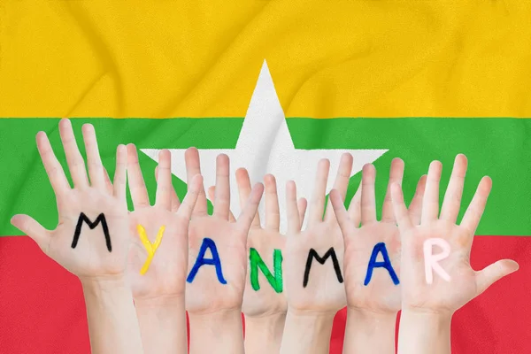 Inschrift Myanmar auf den Händen der Kinder vor dem Hintergrund einer schwenkenden Fahne der Myanmar — Stockfoto