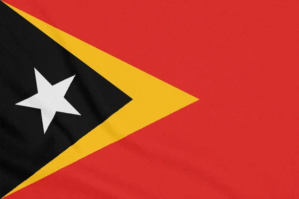 Bandera de Timor Oriental sobre tela texturizada. Símbolo patriótico — Foto de Stock