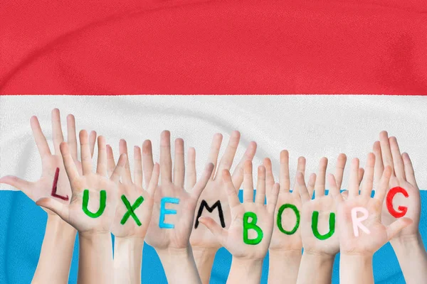 Prasasti Luksemburg di tangan anak-anak dengan latar belakang bendera melambaikan Luksemburg — Stok Foto