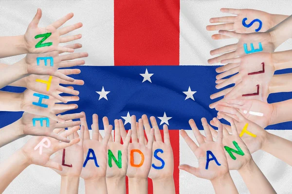 Inscription Netherlands Antilles on the children\'s hands against the background of a waving flag of the Netherlands Antilles