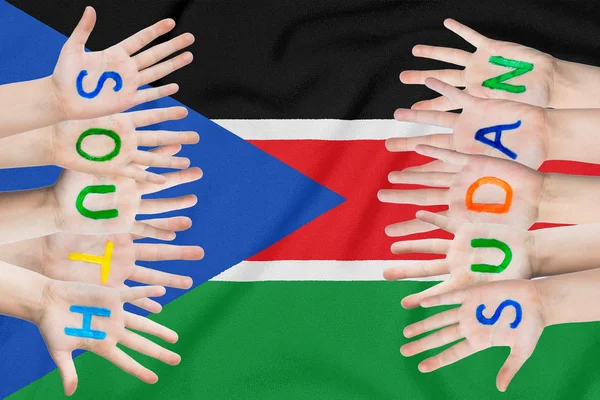 Inscription South Sudan on the children\'s hands against the background of a waving flag of the South Sudan