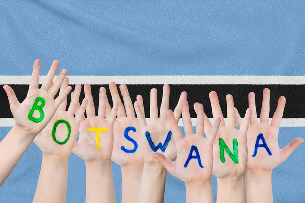 Inscripción Botswana en las manos de los niños sobre el fondo de una bandera ondeante de la Botswana — Foto de Stock
