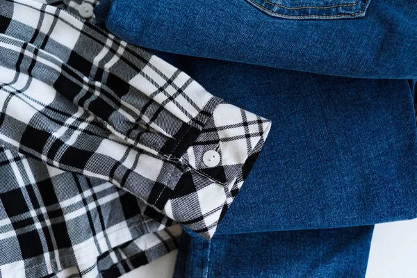 Clothes concept. Checkered shirt and jeans on wooden background. Details