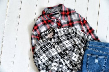 Kıyafet konsepti. Ahşap bir arka plan üzerinde iki damalı gömlek ve kot pantolon. Üstte görüntü